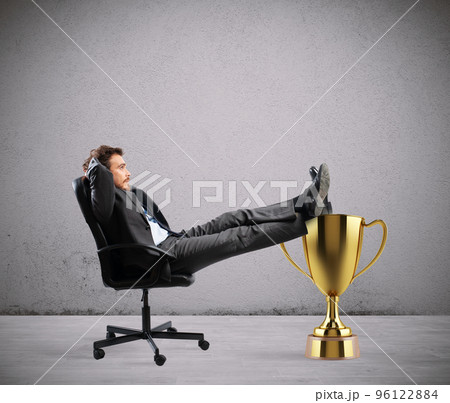 Winner businessman relaxing over a golden cup 96122884