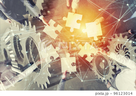 Teamwork of partners. Concept of integration and startup with puzzle pieces and gear overlay. double exposure with network effects 96123014
