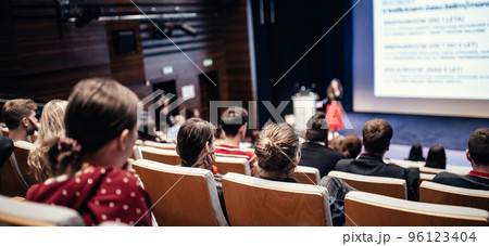 Business and entrepreneurship symposium. Female speaker giving a talk at business meeting. Audience in conference hall. Rear view of unrecognized participant in audience. Business and entrepreneurship symposium. Female speaker giving a talk at business meeting. Audience in conference hall. Rear view of unrecognized participant in audience. 96123404