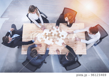 Teamwork of partners. Concept of integration and startup with puzzle pieces. double exposure Teamwork of partners. Concept of integration and startup with puzzle pieces. double exposure 96123469