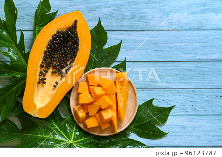 papaya fruits on blue backgroud, fresh ripe papaya slice cut in half tropical fruit with papaya seed and leaf leaves from papaya tree 96123787
