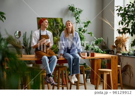 Professional floral artist talking and smiling sitting on table Professional floral artist talking and smiling sitting on table 96129912