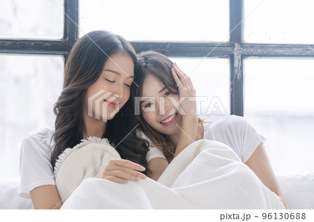 Romantic asian lgbt couple woman sitting together wake up on white bed with pillow in morning home Romantic asian lgbt couple woman sitting together wake up on white bed with pillow in morning home 96130688