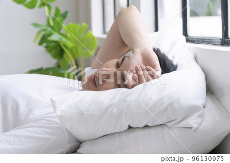 Fatigue asian man sleeping on white pillow with green tree beside window in morning. Tired pressure  96130975