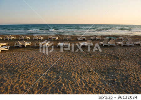 White sunbeds in a sandy beach at sunset White sunbeds in a sandy beach at sunset 96132034