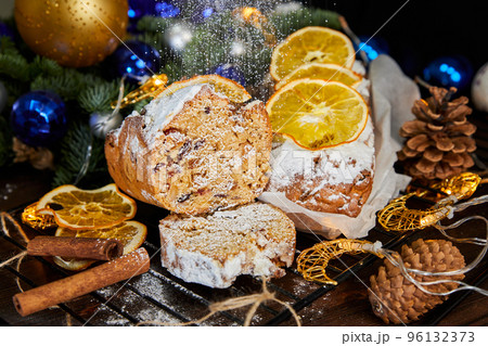 Christmas stollen with spices, raisins, nuts and candied fruits on a background of glowing garlands 96132373
