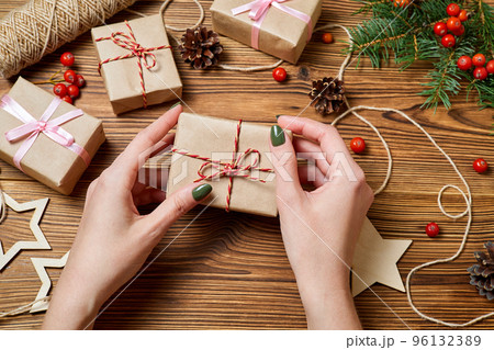 The girl holds in her hand a gift box on the background of christmas accessories The girl holds in her hand a gift box on the background of christmas accessories 96132389
