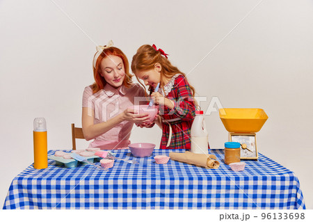 Portrait of mother and daughter cooking cake together isolated over grey background. Spending time together 96133698