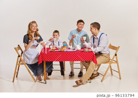 Cheerful happy family, beautiful wife, two sons and husband sitting at the table and having breakfast Cheerful happy family, beautiful wife, two sons and husband sitting at the table and having breakfast 96133794
