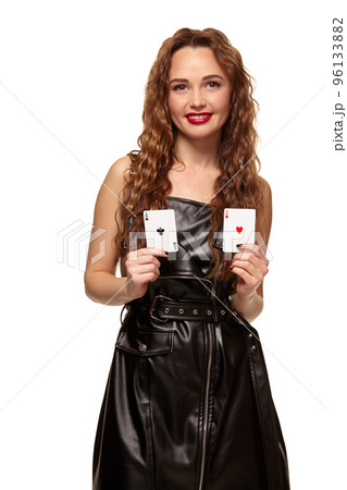 Pretty young redhead or brown-haired woman holding pair of aces in black leather dress isolated on white Pretty young redhead or brown-haired woman holding pair of aces in black leather dress isolated on white 96133882