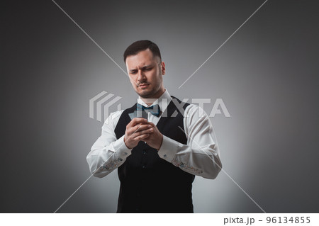 Young man in shirt and waistcoat watch his poker cards, studio shot 96134855