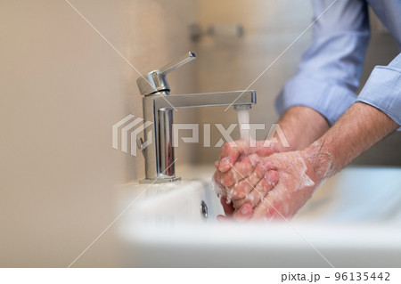 Man using soap and washing hands under the water tap. Hygiene concept hand closeup detail. Man using soap and washing hands under the water tap. Hygiene concept hand closeup detail. 96135442