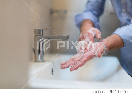 Man using soap and washing hands under the water tap. Hygiene concept hand closeup detail.  96135452