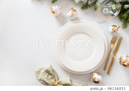 Beautiful Christmas festive table setting with white plate, golden balls on white. 96136851