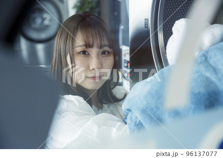 コインランドリーで洗濯をする若い女性 96137077