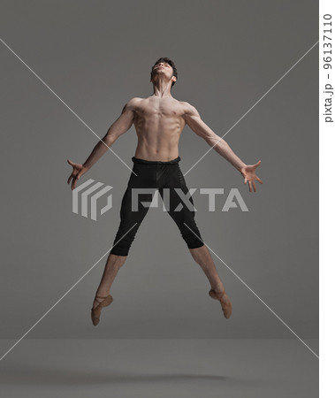 Portrait of young muscular man, ballet dancer performing isolated over dark grey studio background. Metamorphosis 96137110