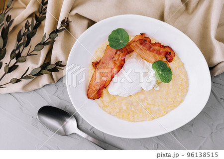 Savory oatmeal porridge with poached egg and bacon 96138515