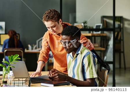 Two young managers or designers in casualwear looking at laptop screen while preparing for presentation or working over new project Two young managers or designers in casualwear looking at laptop screen while preparing for presentation or working over new project 96140113