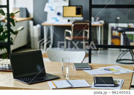 Workplace of economist or accountant with laptop, notebook with pen, glass of water and financial documents in openspace office 96140502