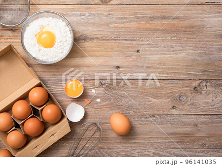 Tray with raw eggs and flour with yolk and kitchen towel on wooden table background. Tray with raw eggs and flour with yolk and kitchen towel on wooden table background. 96141035