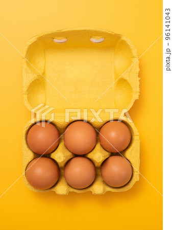 Brown bio organic eggs in paper tray on yellow background.Top view Brown bio organic eggs in paper tray on yellow background.Top view 96141043