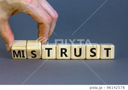 Mistrust or trust symbol. Businessman turns wooden cubes, changes words 'mistrust' to 'trust'. Beautiful grey table, grey background. Business and mistrust or trust concept, copy space. 96142578