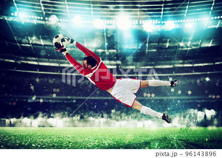 Goalkeeper catches the ball in the stadium during a football game. Goalkeeper catches the ball in the stadium during a football game. 96143896