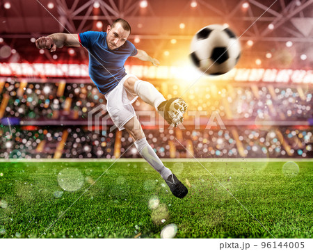 Football scene at night match with player kicking the ball with power. 96144005