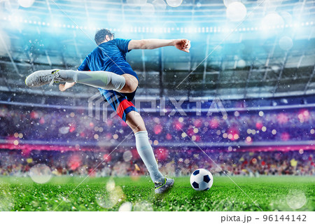 Football scene at night match with player kicking the ball with power. 96144142