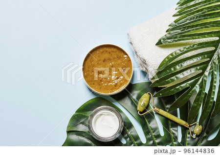 some skin care products on a blue background with green leaves and white towels around it, including an avocaa leaf some skin care products on a blue background with green leaves and white towels around it, including an avocaa leaf 96144836