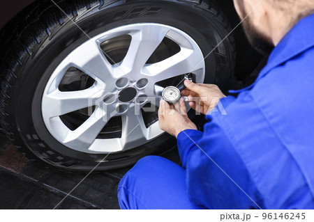 Mechanic checking tire air pressure at car service, closeup 96146245