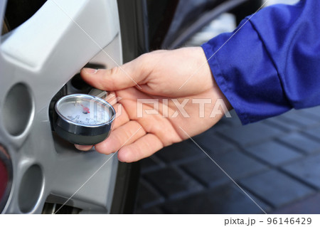 Mechanic checking tire air pressure at car service, closeup 96146429