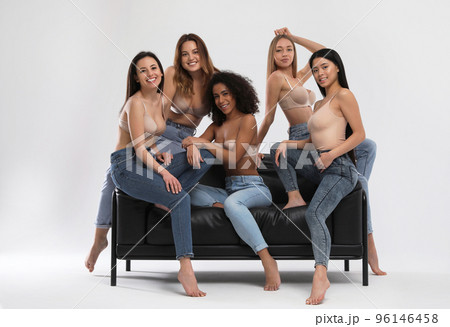 Group of women with different body types in jeans and underwear taking selfie against light 96146458