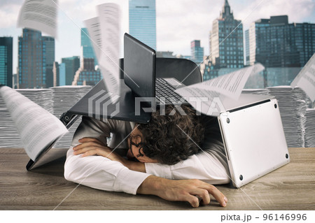 Tired businessman sleeping under a pile of laptops due to workload 96146996