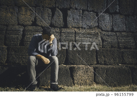 Asia you man sitting alone.He sitting alone beside old wall.man very sad and depressed. 96155799