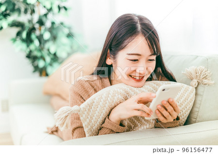 ソファでスマホを使う笑顔の日本人女性 ソファでスマホを使う笑顔の日本人女性 96156477