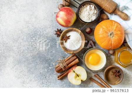 Baking food background. Pumpkins, apples, honey, nuts and seasonal spices for pumpkin or apple pie on a gray tabletop. View from above. Copy space. 96157613