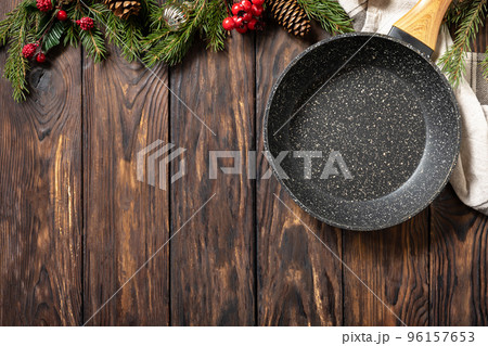 Empty cooking frying pan with tablecloth, Christmas tree and decor on wooden background. Flat mock up for design. View from above. 96157653