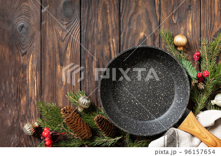 Empty cooking frying pan with tablecloth, Christmas tree and decor on wooden background. Flat mock up for design. View from above. Copy space. Empty cooking frying pan with tablecloth, Christmas tree and decor on wooden background. Flat mock up for design. View from above. Copy space. 96157654