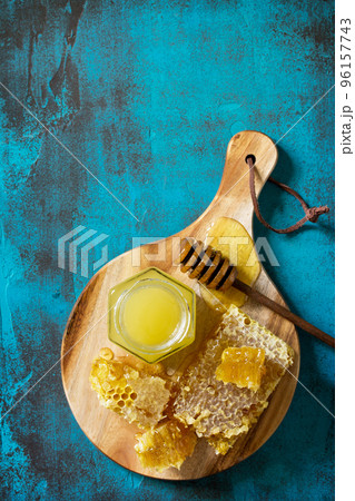 Natural Honey. Honey in glass jar and dipper, Sweet Honeycombs on blue stone table. Top view flat lay background. Copy space. Natural Honey. Honey in glass jar and dipper, Sweet Honeycombs on blue stone table. Top view flat lay background. Copy space. 96157743