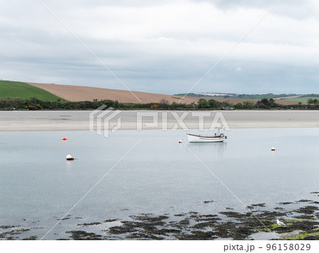 A motor boat moored in shallow water. Calm water surface. Picturesque hills on the shore of the bay. The sandy shore of the Atlantic Ocean. 96158029