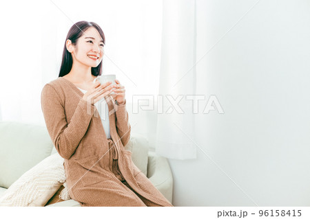 ホットドリンクを飲む女性（お茶・コーヒー・温活・ソファ） 96158415