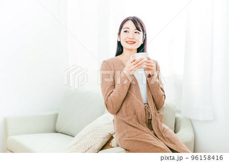 ホットドリンクを飲む女性（お茶・コーヒー・温活・ソファ） 96158416