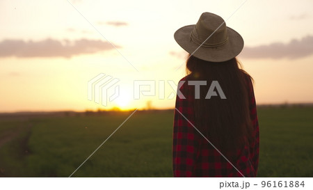 farmer walking along road sunset. work field with green wheat sprouts. agriculture.farming concept. feet rubber boots agronomist walk agriculture farm. work farm rural man. woman farmer hat sunset. farmer walking along road sunset. work field with green wheat sprouts. agriculture.farming concept. feet rubber boots agronomist walk agriculture farm. work farm rural man. woman farmer hat sunset. 96161884