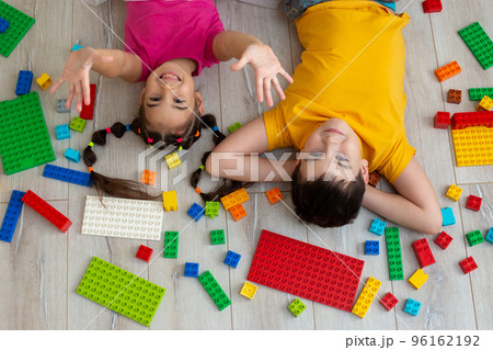 Portrait of happy boy and a little girl, lie on the floor with multicolor constructor 96162192