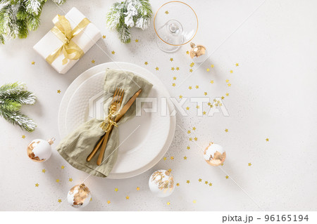 Beautiful Christmas festive table setting with white plate, golden balls on white. 96165194