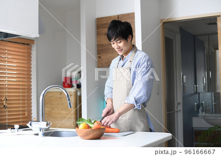 キッチンで料理をするエプロン姿の若い男性 キッチンで料理をするエプロン姿の若い男性 96166667