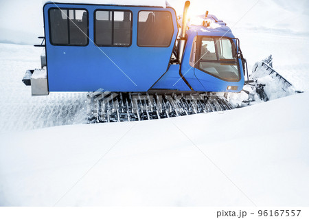 Rear back door window view blue modern snowcat ratrack grooming machine with cabine box preparing ski slope piste alpine skiing resort. ATV arctic vehicle forest winter tundra trip adventure travel 96167557