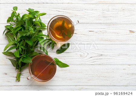 Cup of mint tea on table background. Green tea with fresh mint top view with copy space 96169424