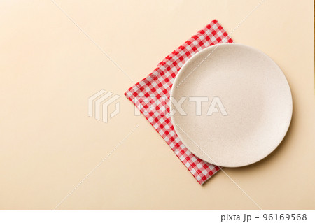 Top view on colored background empty round white plate on tablecloth for food. Empty dish on napkin with space for your design Top view on colored background empty round white plate on tablecloth for food. Empty dish on napkin with space for your design 96169568